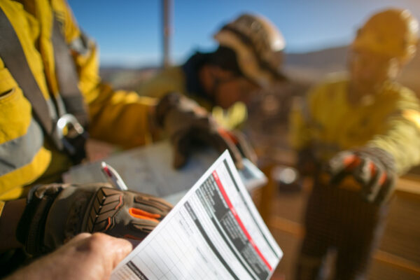 Defocused of construction worker wearing a industry safety glove signing off high risk working at heights permit on the opening field prior starting early day shift