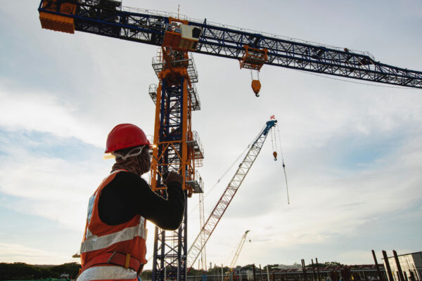 Rigger signal crane at construction site with walkie;talkie